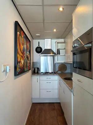 a kitchen with white cabinets and a painting on the wall at Apartment Fleurette in Zandvoort