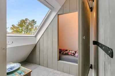 an attic room with a window in a house at Luxury apartment in farmhouse near Amsterdam in Ilpendam