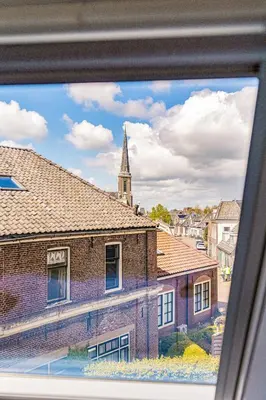 a view from a window of a brick building with a church at Authentic apartment in farmhouse near Amsterdam in Ilpendam