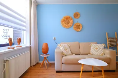 a living room with a couch and a blue wall at Blue Wave in Egmond aan Zee