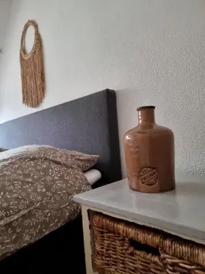 a vase sitting on a table next to a bed at Blue Wave in Egmond aan Zee