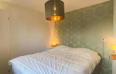 a bedroom with a white bed and two lamps at Klein Maar Fijn in Bergen