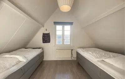 two beds in a attic room with a window at Klein Maar Fijn in Bergen