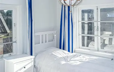 a white bedroom with a bed and two windows at Nautilus 1 in Bergen aan Zee
