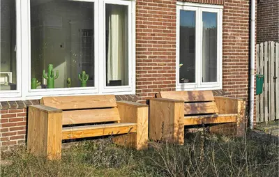 two wooden benches sitting outside of a brick building at Nautilus 1 in Bergen aan Zee