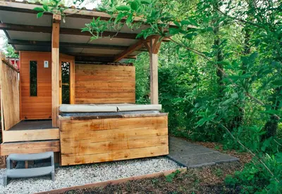 a wooden out house with a bench and a chair at Farmhouse, Jacuzzi, Sauna, BBQ grill & Garden, Sleeps 24 in Kockengen