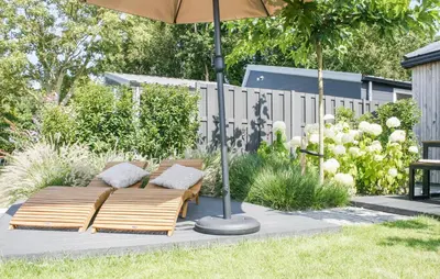 a wooden couch under an umbrella in a garden at Lovely Home In Oostwoud With Wifi in Oostwoud
