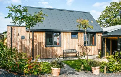 a wooden house with a black roof at Lovely Home In Oostwoud With Wifi in Oostwoud