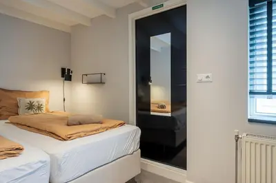 a white bedroom with a bed and a mirror at SATORI LODGE near the Dunes & the Beach in Zandvoort