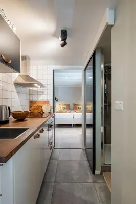 a kitchen with white cabinets and a bed in the background at SATORI LODGE near the Dunes & the Beach in Zandvoort
