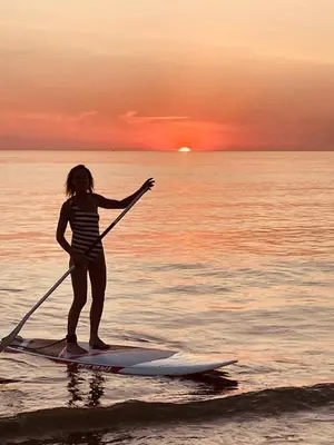 a girl is standing on a paddle board in the water at SATORI LODGE near the Dunes & the Beach in Zandvoort
