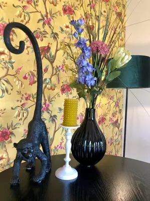 a black statue next to a vase with flowers on a table at Life Contains Beautiful Things in Almere