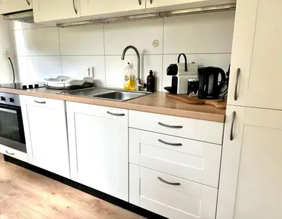 a kitchen with white cabinets and a sink at Cozy family house with spacious garden in the nature near Amsterdam in Vijfhuizen