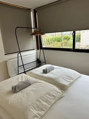 two white beds in a room with a window at Cozy family house with spacious garden in the nature near Amsterdam in Vijfhuizen