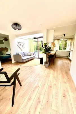 a large living room with wooden floors and a couch at Cozy family house with spacious garden in the nature near Amsterdam in Vijfhuizen