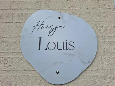 a white sign on a wall with the wordsikeeus at Huisje Louis in Zandvoort