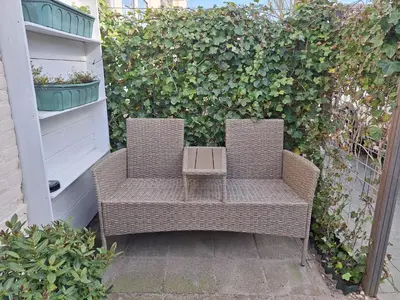 two wicker chairs sitting in front of a hedge at Huisje Louis in Zandvoort