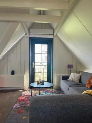 a living room with a couch and a table at De hoftuin Ilpendam appartement in Ilpendam