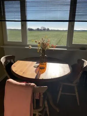 a wooden table with a vase of flowers in a window at De hoftuin Ilpendam appartement in Ilpendam