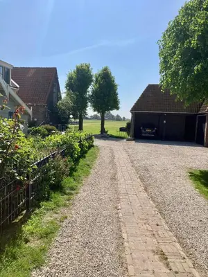 a dirt road in front of a barn at De hoftuin Ilpendam appartement in Ilpendam