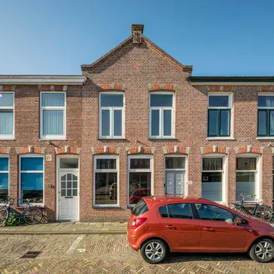a red car parked in front of a brick building at Luxury City Home Alkmaar nearby Amsterdam. in Alkmaar