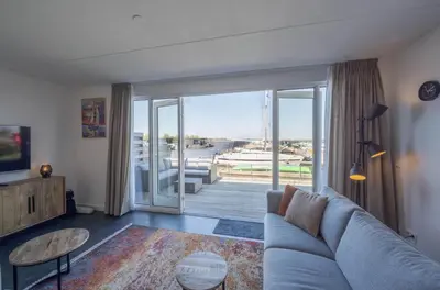 a living room with a couch and a sliding glass door at Meerzicht 24 - Luxury family accommodation with beautiful lake side view in Uitgeest