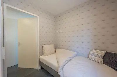 a small bedroom with a bed and a mirror at Meerzicht 24 - Luxury family accommodation with beautiful lake side view in Uitgeest