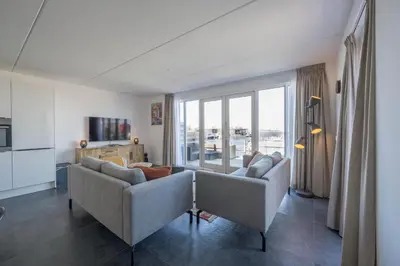 a living room with two couches and a large window at Meerzicht 24 - Luxury family accommodation with beautiful lake side view in Uitgeest