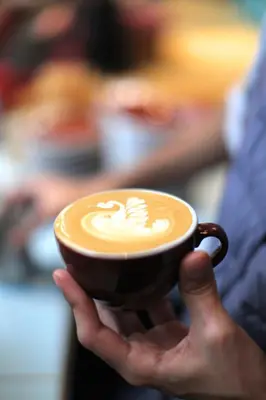 a person holding a cup of coffee with a latte at Poppies in Amsterdam