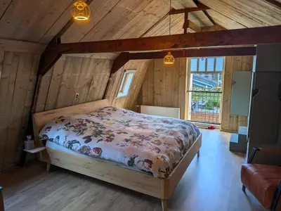 a bedroom with a bed in a room with wooden walls at De oude walnoot in Sint Pancras