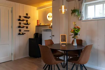 a dining room with a table and chairs and a refrigerator at De oude walnoot in Sint Pancras