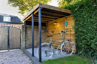 a bike is parked under a wooden shed at De oude walnoot in Sint Pancras