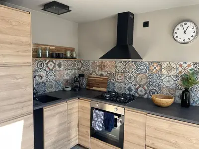 a kitchen with a stove and a clock on the wall at Modern guest house. in Bergen