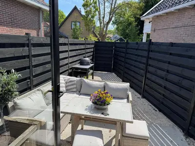 a patio with a couch and a table with flowers at Modern guest house. in Bergen