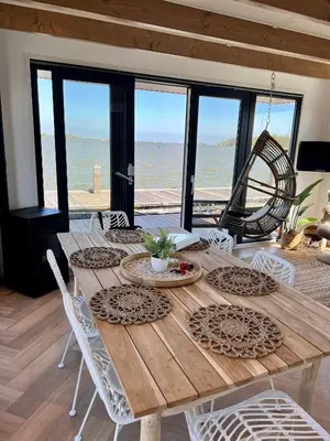 a wooden table with white chairs and a view of the ocean at Luxury Houseboat Liberdade with sauna and dinghy in Monnickendam
