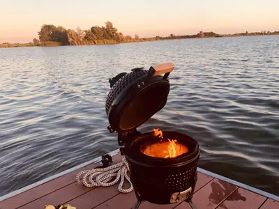 a fire pit on a dock next to the water at Luxury Houseboat Liberdade with sauna and dinghy in Monnickendam