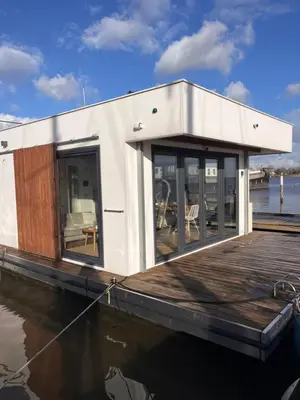 a small house on a boat on the water at Luxury Houseboat Liberdade with sauna and dinghy in Monnickendam