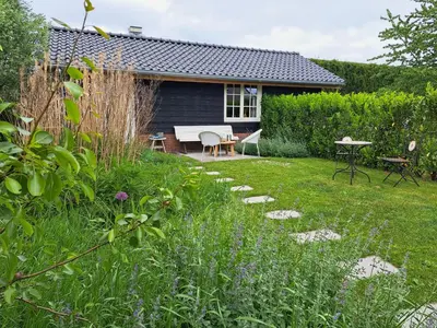 a garden with a table and a bench and a house at Het Buitenleven in Spaarndam