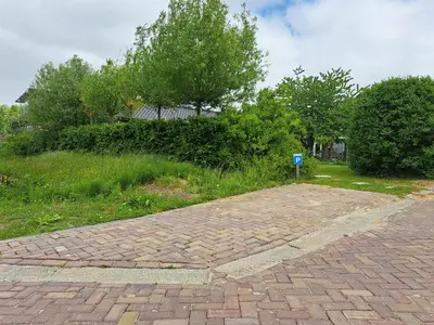 a brick road with a blue sign in a yard at Het Buitenleven in Spaarndam