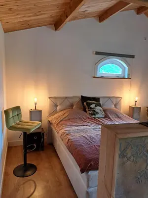 a bedroom with a bed with a window and a chair at Het Buitenleven in Spaarndam