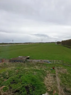 a large green field with a fence in the foreground at Landlust in Purmerend
