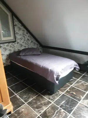 a small bed in a bedroom with a tiled floor at Landlust in Purmerend