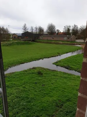 a river in a field next to a building at Landlust in Purmerend
