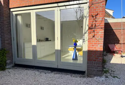 a large sliding glass door with a vase in it at Aventure, beach 500m, free parking in Noordwijk