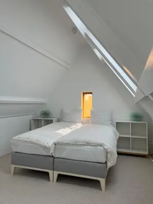 a white bedroom with a bed in a attic at Aventure, beach 500m, free parking in Noordwijk