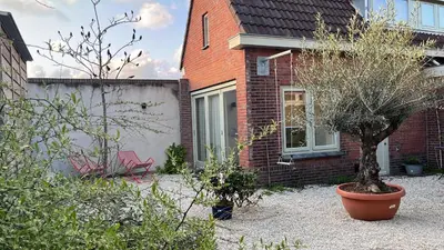 a house with two trees and a chair in a yard at Aventure, beach 500m, free parking in Noordwijk