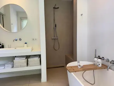 a bathroom with a tub and a sink and a mirror at Het Bosch in Bergen