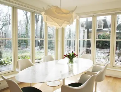 a dining room with a white table and chairs and windows at Het Bosch in Bergen