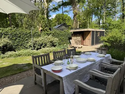 a table with plates and glasses on it in a garden at Het Bosch in Bergen