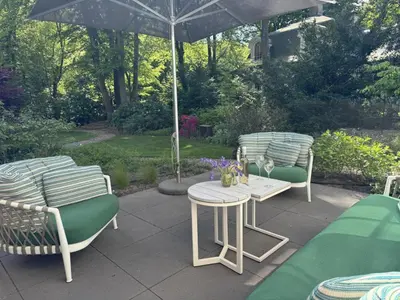 a patio with three chairs and a table and an umbrella at Het Bosch in Bergen